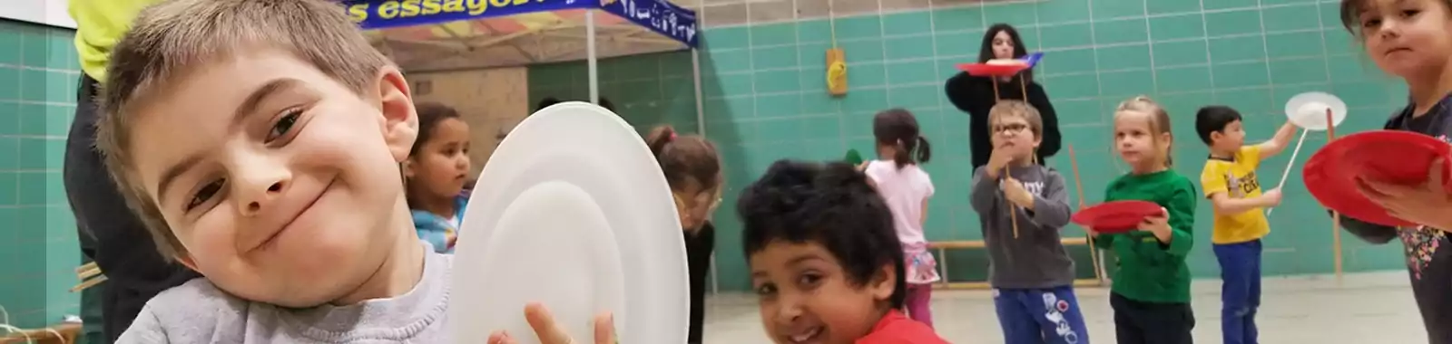 Des enfants souriants s’amusent avec leurs assiettes chinoises pendant un atelier 100 % Cirque